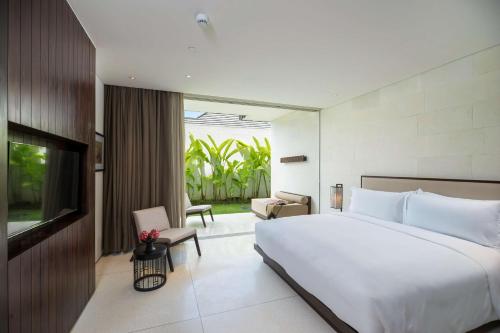 a bedroom with a large white bed and a television at Studios at Alila Seminyak in Seminyak