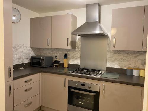 a kitchen with white cabinets and a stove top oven at Spacious 2 Bed House for Corporate and Family Stays in Basingstoke
