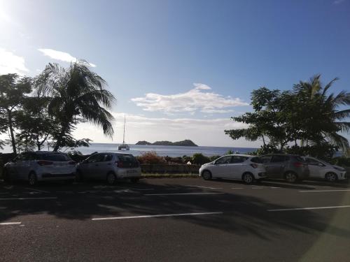 a group of cars parked in a parking lot near the water at Appartement avec vue sur mer in Bouillante