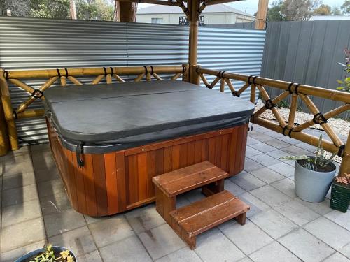 a wooden hot tub sitting on a patio with a stool at Investigator Beach Breeze Apartments U3 in Kingscote