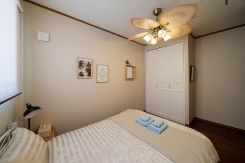 a bedroom with a bed and a ceiling fan at ペンション ラナカイハウス沖縄 in Onna