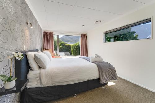 a bedroom with a large bed and a large window at Riverside Three Bedroom - Remarkable Views in Queenstown