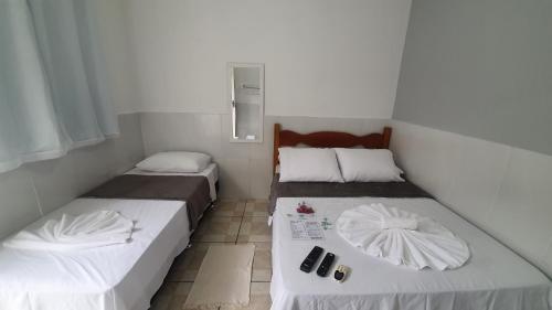 duas camas num pequeno quarto com lençóis brancos em Pousada Pérola Verde em Abraão