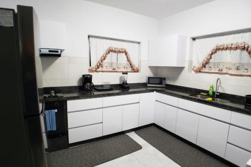 een keuken met witte kasten en zwarte aanrechtbladen bij Aruba Vacation House - Cozy and Modern! in Oranjestad