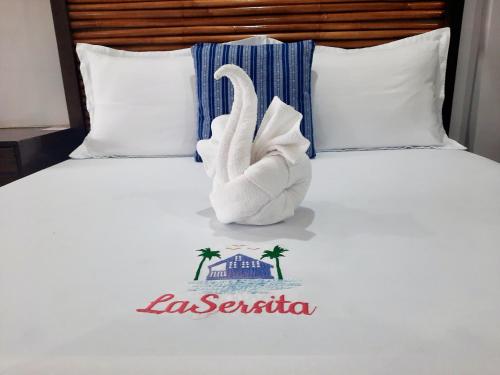 a towel swan on a bed with the name of a resort at LaSersita Casitas and Water Spa Beach Resort by Cocotel 