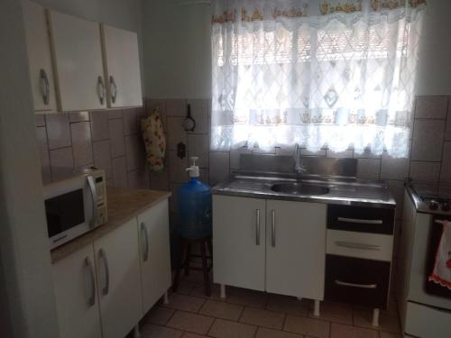a kitchen with a sink and a microwave and a window at Casa de praia navegantes, próximo aeroporto in Navegantes