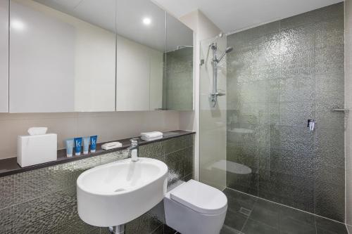 a bathroom with a toilet and a sink and a shower at Meriton Suites North Sydney in Sydney