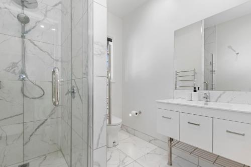a white bathroom with a shower and a sink at Paihia Paradise - Paihia Holiday Home in Paihia