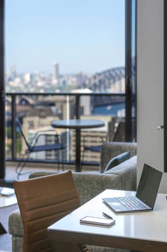 a laptop sitting on a table with a view of a city at Meriton Suites North Sydney in Sydney