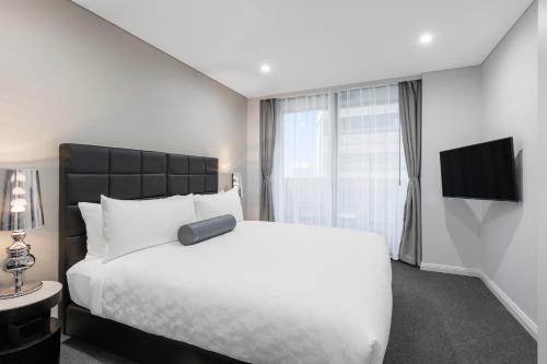 a bedroom with a large white bed and a television at Meriton Suites North Sydney in Sydney