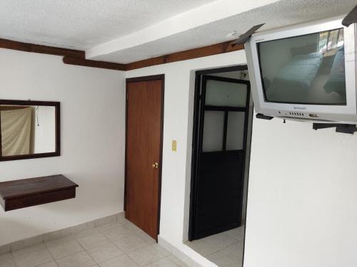 a room with a tv on a wall with a door at Hotel Tivoli in San Cristóbal de Las Casas