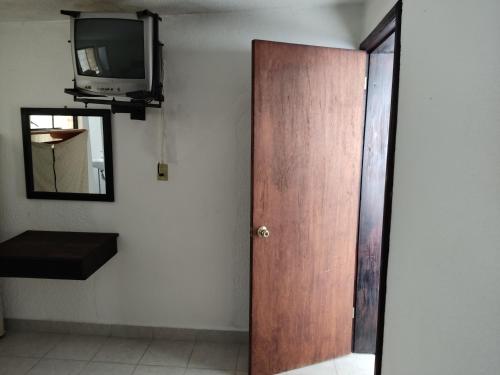 a room with a door and a tv and a mirror at Hotel Tivoli in San Cristóbal de Las Casas