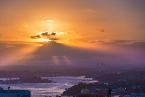 a sunset over the ocean with a mountain in the background at Meriton Suites North Sydney in Sydney