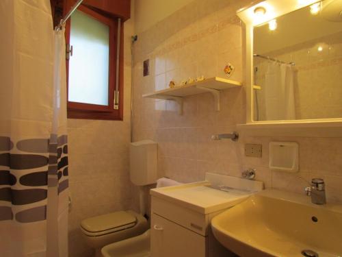 uma casa de banho com um lavatório, um WC e um espelho. em Lovely flat with garden and pool - Beahost em Bibione