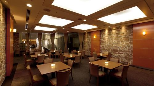 ein Restaurant mit Tischen und Stühlen und einer Steinmauer in der Unterkunft Hotel Grand Hill Ichigaya in Tokio