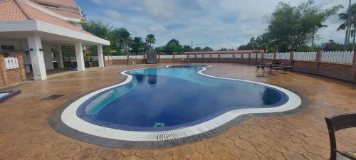 a swimming pool on a patio with a house at Kuala Terengganu Golf Resort by Ancasa Hotels & Resorts in Kuala Terengganu