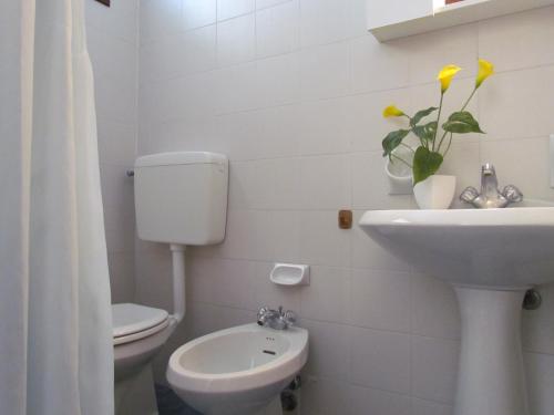 een witte badkamer met een toilet en een wastafel bij Holiday in Bibione by the beach - Beahost in Bibione