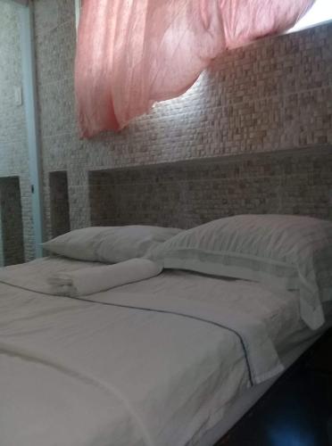 uma cama com lençóis brancos e almofadas num quarto em Villa Julirous Rd spa and ApartHotel Camp for vacationers 2 bedrooms em Boca Chica