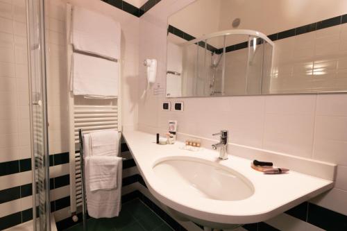 a white bathroom with a sink and a mirror at Hotel Enzo Moro in Sùtrio