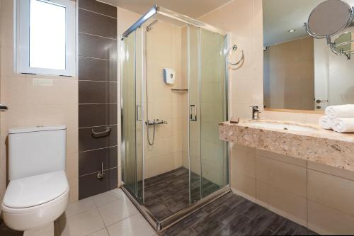 a bathroom with a shower and a toilet and a sink at Aeolian Village Beach Resort in Skala Eresou