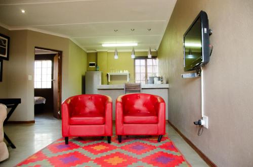 two red chairs sitting on a rug in a room at Desert Dew Guest House in Hutchinson