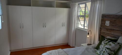 um quarto com armários brancos, uma cama e uma janela em StayMore em East London