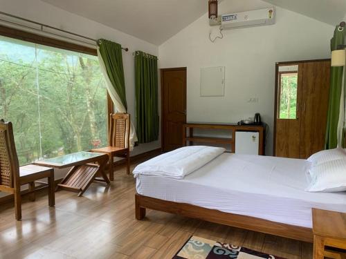 a bedroom with a bed and a table and chairs at Nutmeg valley in Idukki