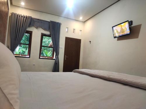 - une chambre avec un lit et une télévision murale dans l'établissement Mudhia Homestay, à Magelang