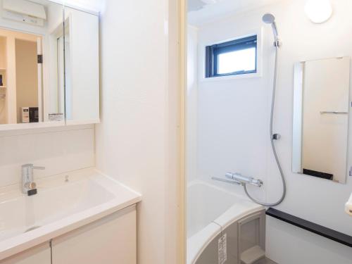 a white bathroom with a shower and a sink at Family Inn Kei 慶 in Kyoto