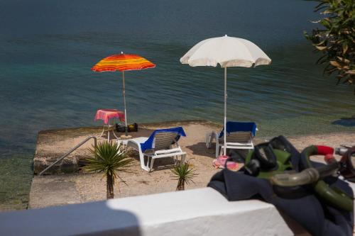 zwei Sonnenschirme und Stühle am Strand mit Wasser in der Unterkunft Seaside Studio in Zaton