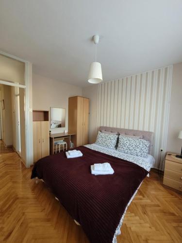 een slaapkamer met een groot bed en 2 handdoeken bij Community Park Apartment in Niš