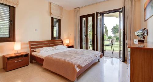 una camera da letto con un letto e una porta scorrevole in vetro di Ground floor apartment with golf and sea views - Roudias, Aphrodite Hills Resort a Kouklia