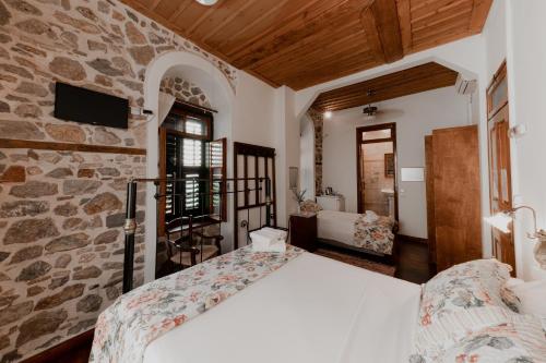 sypialnia z łóżkiem i kamienną ścianą w obiekcie Rigas Pension Nafplio w Nauplionie