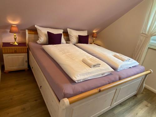 a large bed with white sheets and purple pillows at Haus Petersen in Undeloh