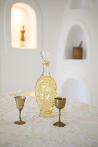 a glass vase sitting on a table with two cups at Aliori art caves in Aegiali