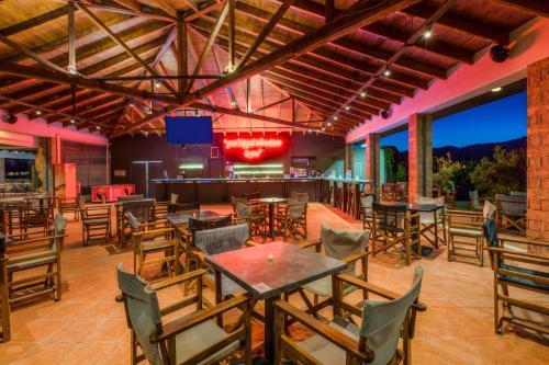 a restaurant with tables and chairs and a bar at Aeolian Village Beach Resort in Skala Eresou