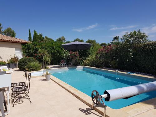 - une piscine avec un parasol à côté d'une maison dans l'établissement Studio Villa Les Canas, à Saint-Gély-du-Fesc