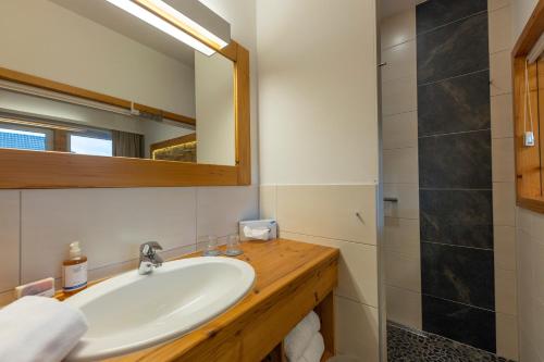 ein Bad mit einem Waschbecken, einem Spiegel und einer Dusche in der Unterkunft Hotel zum Weissensee in Weissensee