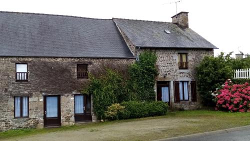 ein altes Backsteinhaus mit rosa Blumen davor in der Unterkunft GITE AVEL BREIZH in Roz-sur-Couesnon