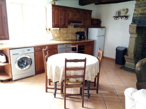 eine Küche mit einem Tisch und einigen Stühlen und einer Spülmaschine in der Unterkunft GITE AVEL BREIZH in Roz-sur-Couesnon