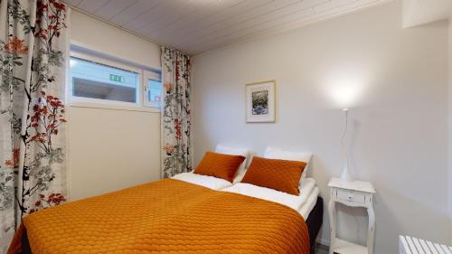 a bedroom with a bed with orange sheets and a window at Starvillas A302 in Kalajoki