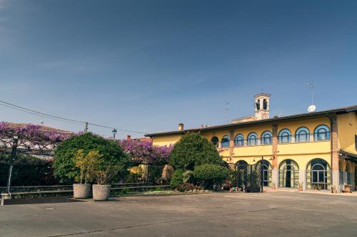 duży żółty budynek z drzewami i fioletowymi kwiatami w obiekcie il Glicine B&B RISTORANTE w mieście Cazzago San Martino