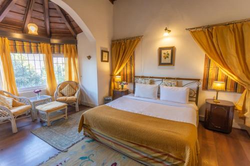um quarto com uma cama, uma cadeira e janelas em Seclude Ramgarh Taradale em Rāmgarh