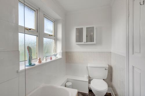 Baño blanco con aseo y lavamanos en Guest Homes - The Lodge, en Earlham