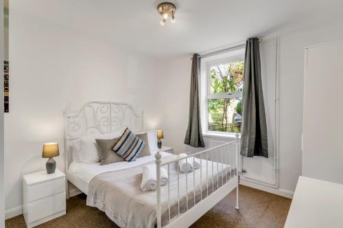 a white bedroom with a crib and a window at Guest Homes - The Lodge in Earlham