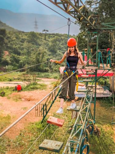 a woman in an orange helmet standing on a rope bridge at Rainforest Resort and Spa, Igatpuri -Nature's Luxury Awaits in Igatpuri
