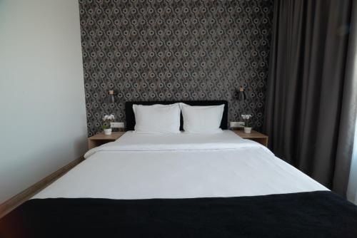 a bedroom with a large white bed and a wall at Vitosha Park Hotel - Free Indoor Pool & Parking in Sofia
