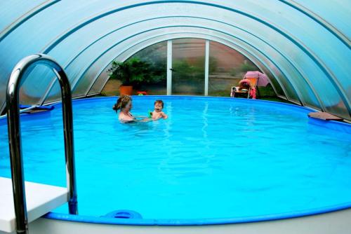 dwójka dzieci pływających w basenie w kształcie kopuły w obiekcie Heidekäfer Ferienhaus Eichhörnchen w mieście Kirchlinteln