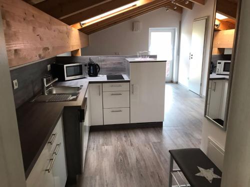 a kitchen with white cabinets and a sink and microwave at Ferienwohnung am Freibad in Schwarzach