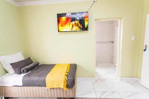 a bedroom with a bed and a tv on the wall at The Hide on kilburn in Roodepoort